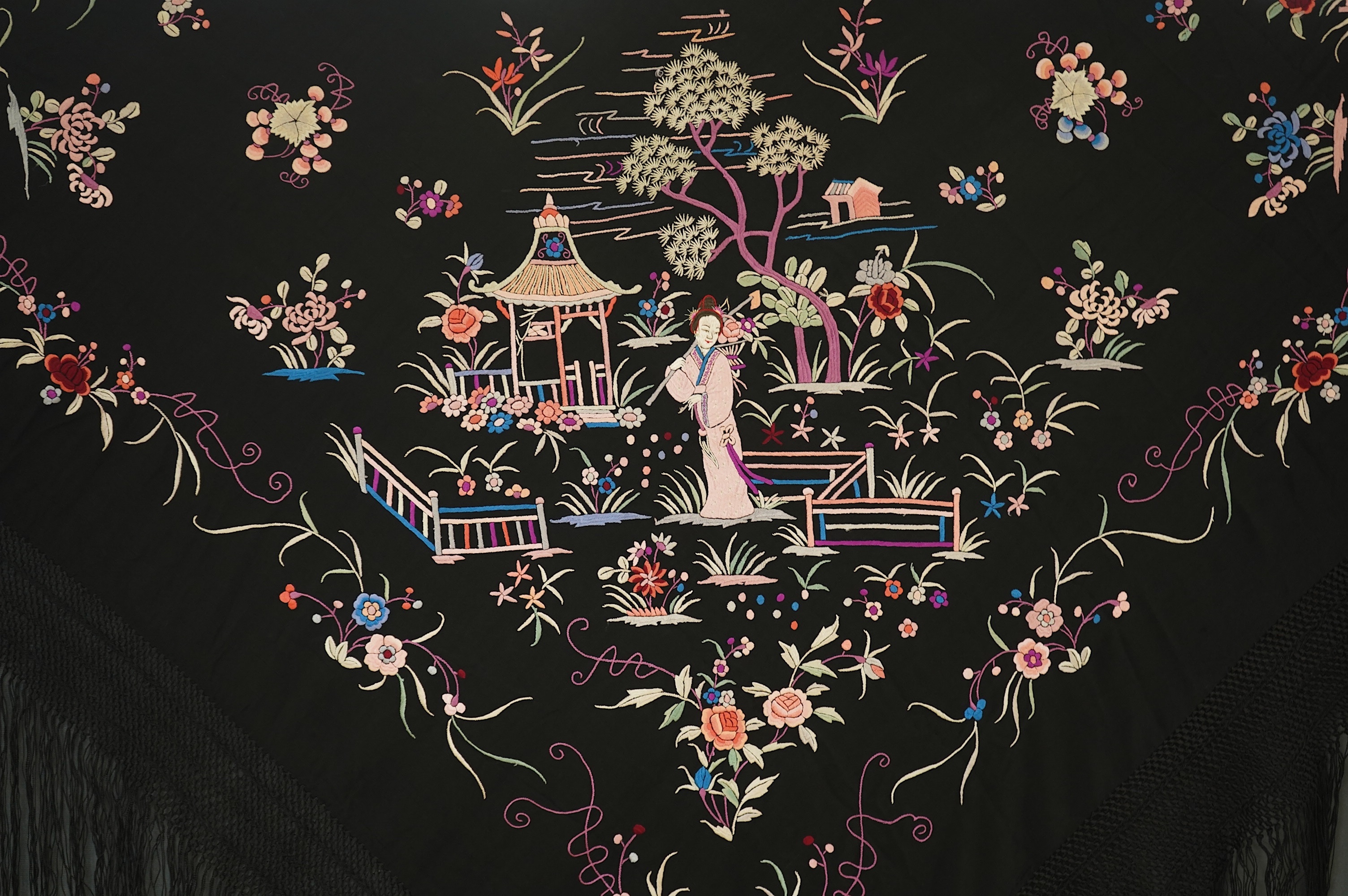 Two Chinese embroidered silk fringed shawls, one cream floral embroidery on cream silk, the other polychrome silk embroidered with figures on black silk, black shawl 130cm x 136cm, cream shawl 128cm x 168cm. Condition -